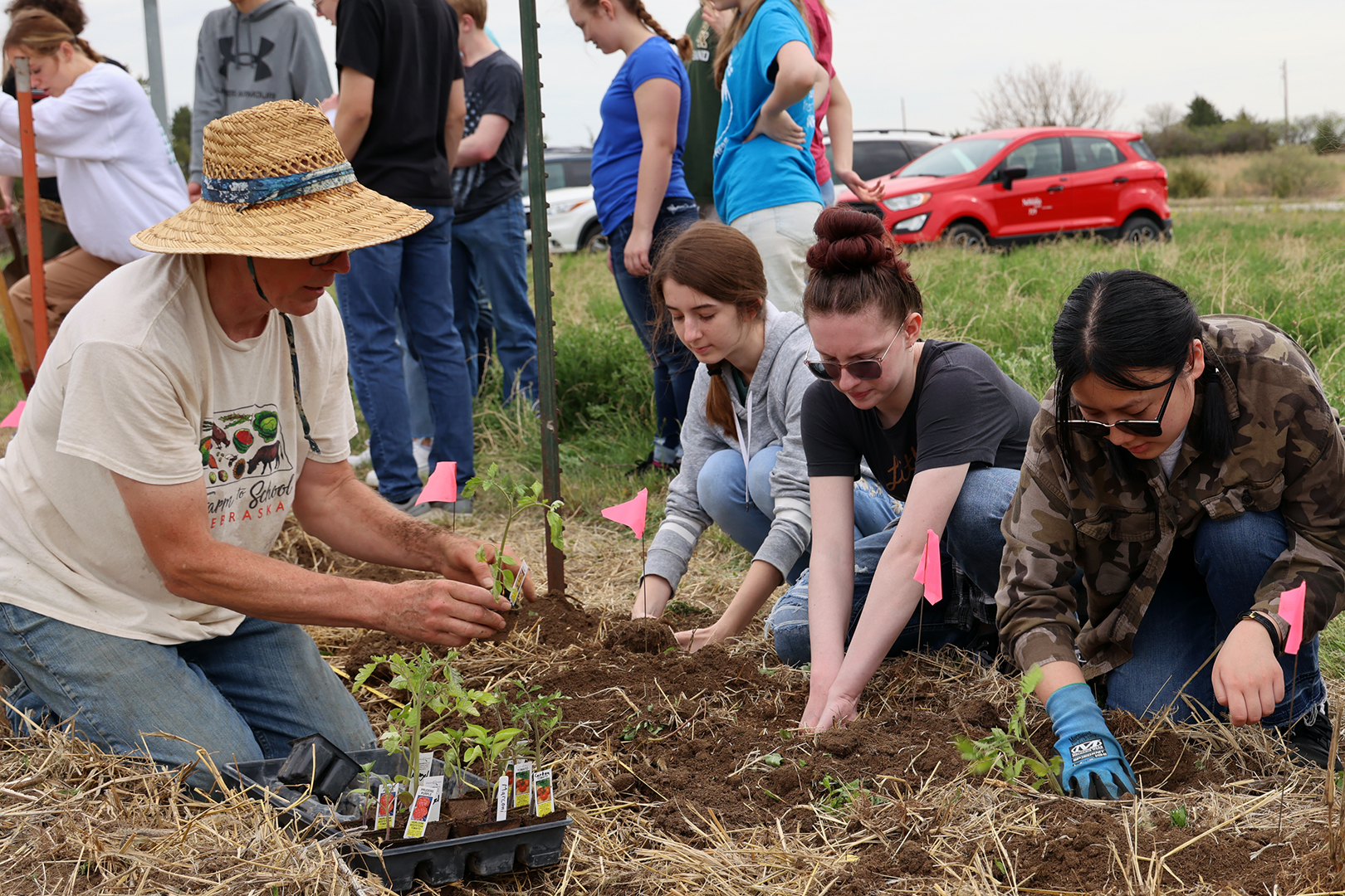 Gary Fehr shows Pius X High School students how to plant vegetables at Green School Farms in Raymond, Neb.