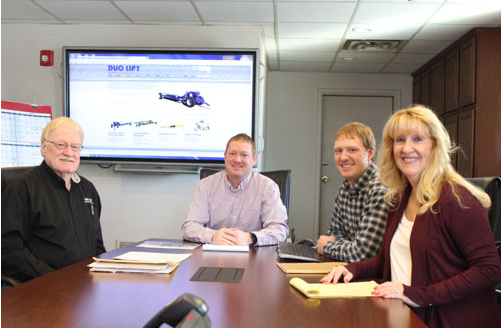 Photo of Hellbusch family around a conference table.