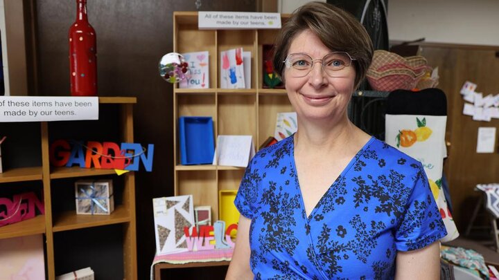 Adeline Johnson stands in front of crafts made by students at Our Place After School Care and sold at the Freedom Factory. Photo by Russell Shaffer