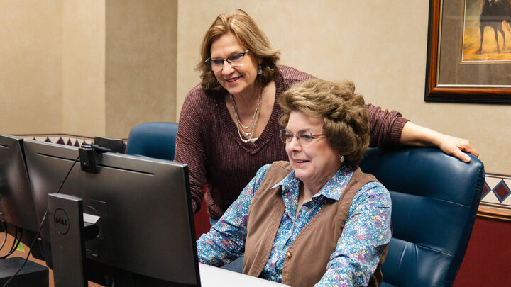 Marilyn Schlake (left) and Cheryl Burkhart-Kriesel work on curriculum for an online community development course through NU Advance.