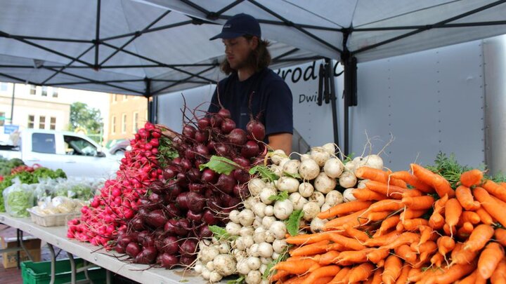 An employee of Pekarek’s Produce, from Dwight, Nebraska, sets up a table to sell produce at the Haymarket Farmers Market in Lincoln. Photo by Russell Shaffer