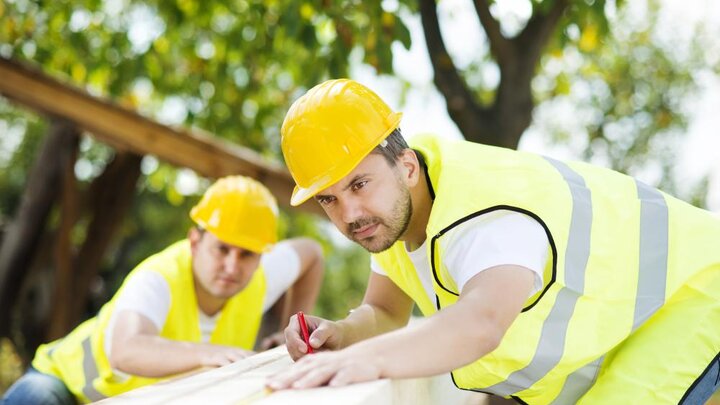 Stock photo of Construction Workers Collaborating On New House Building.