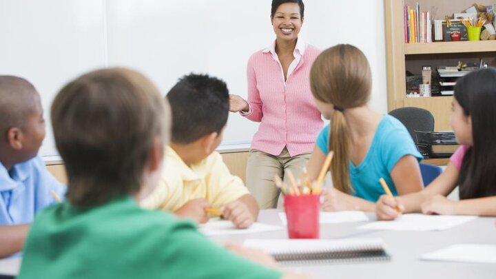 Stock Photo of Elementary School Classroom with Teacher Standing at Board.