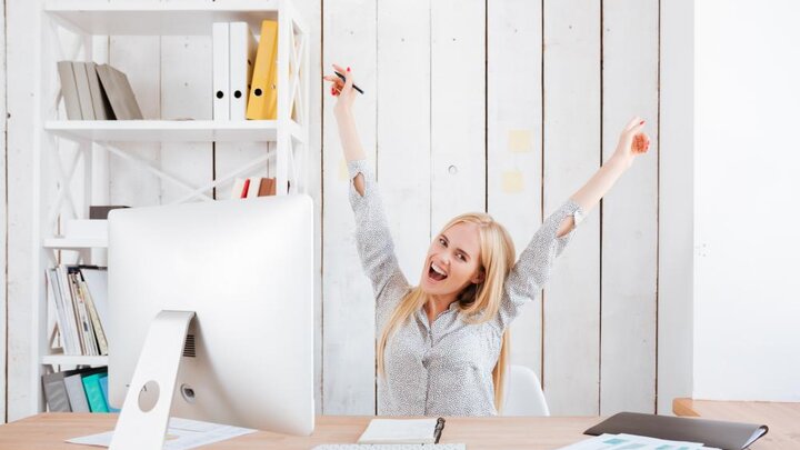 Stock photo of Happy Excited Business Woman Celebrating Success While Sitting At Her Workplace With Hands Raised