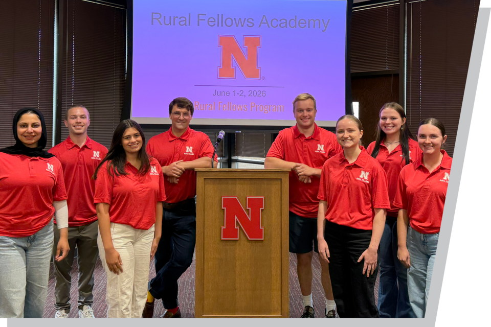 Group of nine people in red shirts standing near a podium with "N" logo under projection.