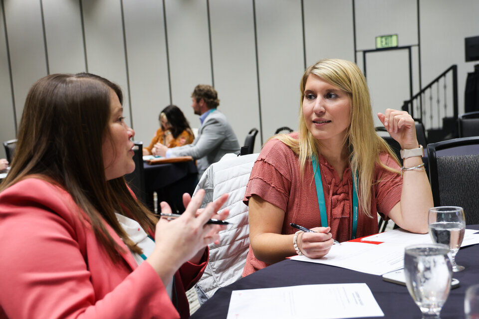 Two women talk at a table during a leadership conference in Kearney, Neb.