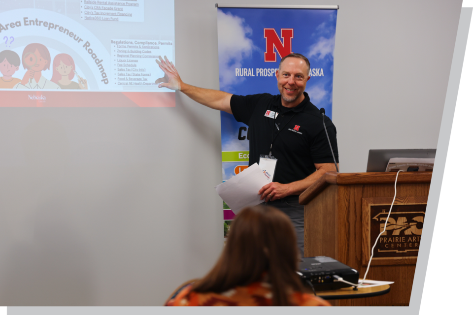 A male RPN Extension educator points to a projection of a PowerPoint presentation as he speaks with an audience.